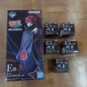 Boxed Naruto Masterlise figure set featuring Naruto in a dark cloak, placed on a wooden floor with several small black boxes beside it