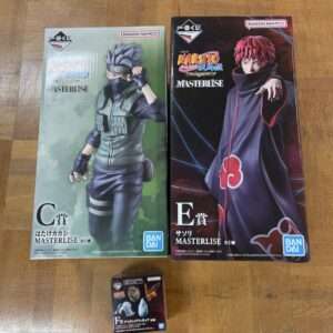 Two Bandai Masterlise collectible figure boxes: Kakashi (green vest) on the left and Itachi in an Akatsuki cloak on the right, with a small figure box in front at the bottom.