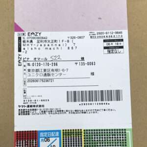 White parcel shipping label with barcode and Japanese text attached to a brown box.