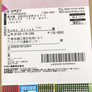 Shipping label on a brown cardboard box with a barcode, Japanese text, sender and recipient details, and a multicolor bottom strip (EAZY branding).