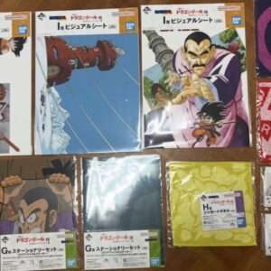 Collection of Dragon Ball EX merchandise laid on a wooden floor: visual sheets, towels, and small boxed accessories in plastic bags and packaging.