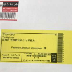 White envelope with a large yellow shipping label containing Japanese text and a barcode; recipient name Federico Jimenez Stevenson visible on the label, plus a small red-and-white label in the upper left corner.