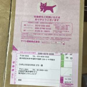 Pink parcel label with a purple cat logo and Japanese shipping details, including sender and recipient addresses and tracking numbers.