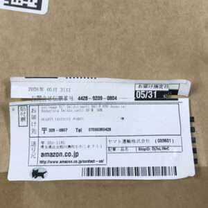 Cardboard package with a white shipping label showing Japanese text, barcode, and Amazon.co.jp reference on the side of the box.