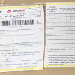 Two attached international shipping documents on a cardboard box: a Korea Post K-Parcel label with barcode and sender/recipient details, and a CN 22 customs declaration form with weight and sender/receiver fields, both bordered in yellow.