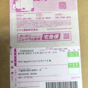 Close-up of a pink Yamato Transport delivery label on a cardboard box, showing recipient address, sender details, barcodes, and QR codes.