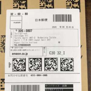 Japanese shipping label on a cardboard box with barcodes, three QR codes, and an address block including amazon.co.jp
