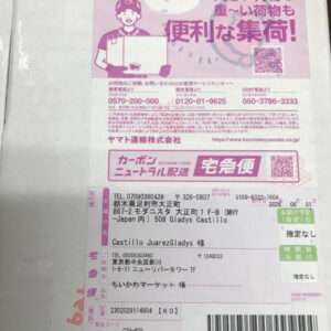 Pink Japanese courier label for Yamato Transport with shipping details, barcode, and address lines visible on a package surface edge.