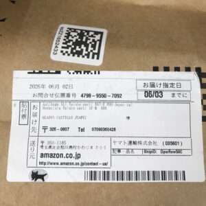 Shipping label on a cardboard box with Japanese text, barcode, and Amazon.co.jp contact/address info visible.