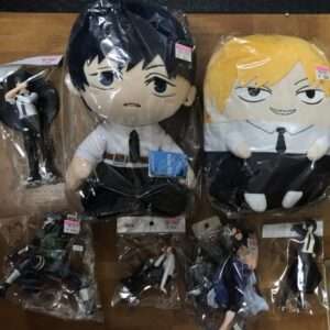 Assorted anime plush toys in plastic packaging laid out on a wooden floor, including two large figures in white shirts and ties.