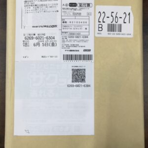 Brown cardboard parcel with a white shipping label and a separate white label showing the large numbers 22-56-21 and a barcode on the right side of the box.