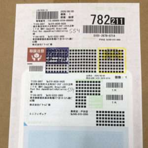 Shipping label with multiple barcodes and Japanese text, likely a parcel tracking tag on brown paper.