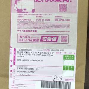 Pink Japanese shipping label on a cardboard box showing recipient info, barcode, and QR codes.
