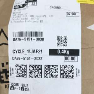 Shipping label on a brown box with barcodes, text like 'GROUND', weight 0.4 kg, and cycle info visible front and center.