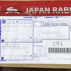 Shipping label with barcode and handwritten recipient details on a cardboard box, blue stamps visible at left edge from Japan Rabbit branding on top edge.
