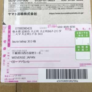 Shipping label on a cardboard box showing recipient name (laura tellez 303 様), address fields, bar code, and green pickup/arrival boxes in Japanese.