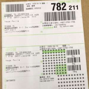 Shipping label on a package with barcodes, tracking numbers, and handwritten details in Japanese; shows weights (2kg/5kg/10kg) and stamps 782 211.