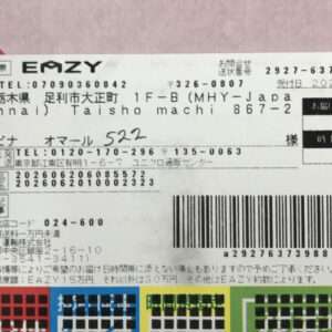 Close-up of a Japanese shipping label with sender/recipient information, a large barcode, and multicolored tracking grids.