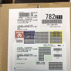 Cardboard box with a large shipping label showing barcodes, Japanese text, and a yellow-highlighted grid pattern near the right side of the label.