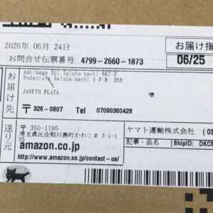 Shipping label on a brown cardboard box with Amazon.co.jp address, Japanese text, and a barcode bar sequence.
