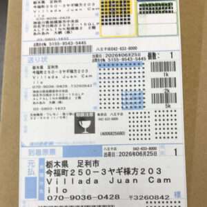 A Japanese shipping label on a cardboard box with multiple sections, barcodes, and printed text including recipient and sender details.