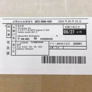 Shipping label on a cardboard package showing sender/recipient info, date 06/27, and a barcode strip at bottom left corner of label.  Articulos Japan (Post Box Japan)