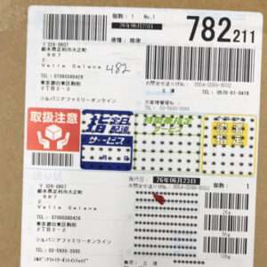 Japanese parcel shipping label with multiple barcodes, stamp, and '取扱注意' warning mark.
