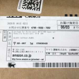 Cardboard box with a white shipping label showing a tracking number (4798-9550-7092) and Amazon.co.jp branding, along with a barcode and a small black animal icon at the bottom left.