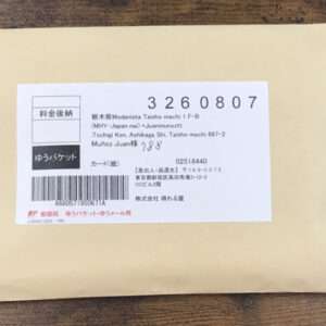 Manila envelope with a white shipping label showing a barcode, Japanese text, and a large printed number.