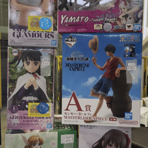 Assorted anime figure boxes on a store shelf, featuring characters from One Piece and other series, arranged in a grid formation with price stickers visible.
