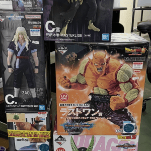 Stack of anime figure boxes on a store shelf featuring Dragon Ball Z and One Piece characters with vibrant artwork and price stickers.
