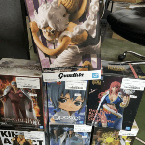 A display of anime figure boxes on a store shelf, centered on a large Monkey D. Luffy Grandista box with others around it.
