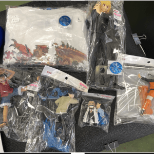 Assorted anime figurines in clear bags laid out on a dark table; includes a Naruto in orange jumpsuit and other character figures with price tags visible.