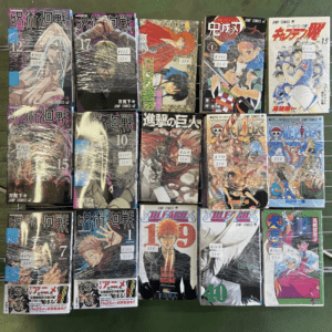 Grid of 15 wrapped manga volumes laid out on a green surface, showcasing colorful action covers and Japanese titles (Jump Comics).