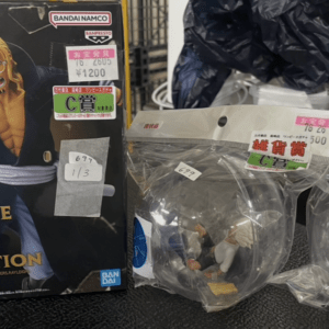 Boxed One Piece Battle Record Collection figure set featuring Luffy on the cover, with price stickers, beside three clear globe display figures in a store.