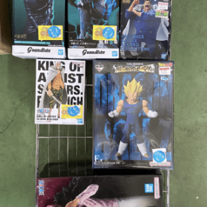 A metal grid shelving unit with multiple boxed action figures, anime and superhero character boxes arranged on shelves, some figures still in packaging on top shelf.