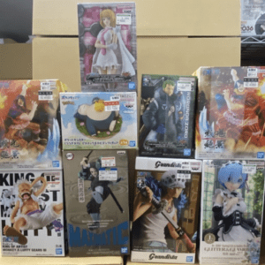 Assorted anime figure boxes stacked on a shelf, showing colorful character poses and packaging art.