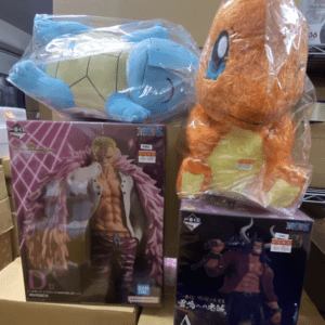 Blue turtle plush and orange plush toys atop boxed figurines on a store shelf.