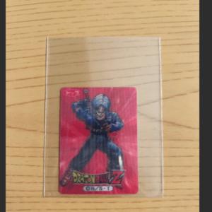 Dragon Ball Z trading card in a clear protective sleeve on a wooden surface.