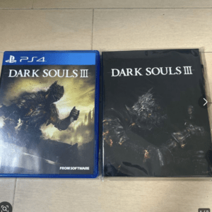 Two Dark Souls III items: a PS4 game case (blue) on the left and a dark, sealed Dark Souls III box on the right.