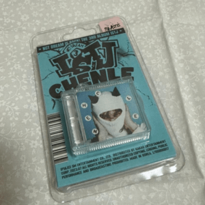Blue card packaging with a small panda figure wearing a white hood inside a clear plastic blister, resting on a patterned fabric surface.