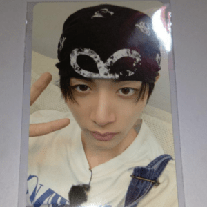 Selfie of a young person wearing a black bandana, white shirt with denim overalls, making a peace sign toward the camera.