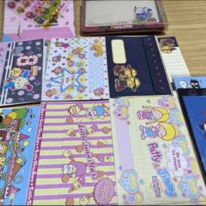 Assorted colorful children’s folders with cartoon characters laid out on a wooden table.