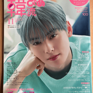 Japanese magazine cover featuring a young man with silvery hair in a mint sweater, resting his chin on his hand; bold pink Japanese title and side text blurbs appear around him.