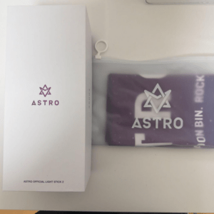 White packaging with the ASTRO logo and 'ASTRO Official Light Stick 2' text beside a purple pouch that also shows the ASTRO logo and star emblem.