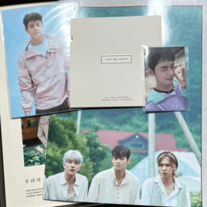 Collage of K-pop photo cards: three men posing outdoors at center, a large portrait on the left, and a smaller portrait on the right, with a white booklet in the middle