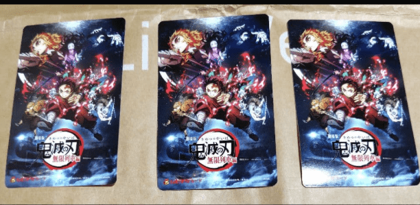 Three identical Demon Slayer posters laid on a brown cardboard surface, each showing colorful action scenes and the logo.