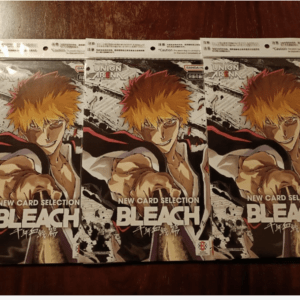 Three Bleach manga covers featuring Ichigo with orange hair, arranged side by side on a wooden table.