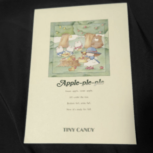 Children's book cover showing a woodland picnic with rabbits and a bear under a tree; title 'Apple-ple-ple' and 'Tiny Candy' at the bottom.