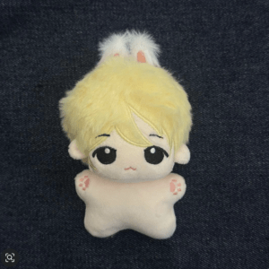 Cute plush toy with blond hair, big black eyes, and a white star-shaped body on dark denim background.